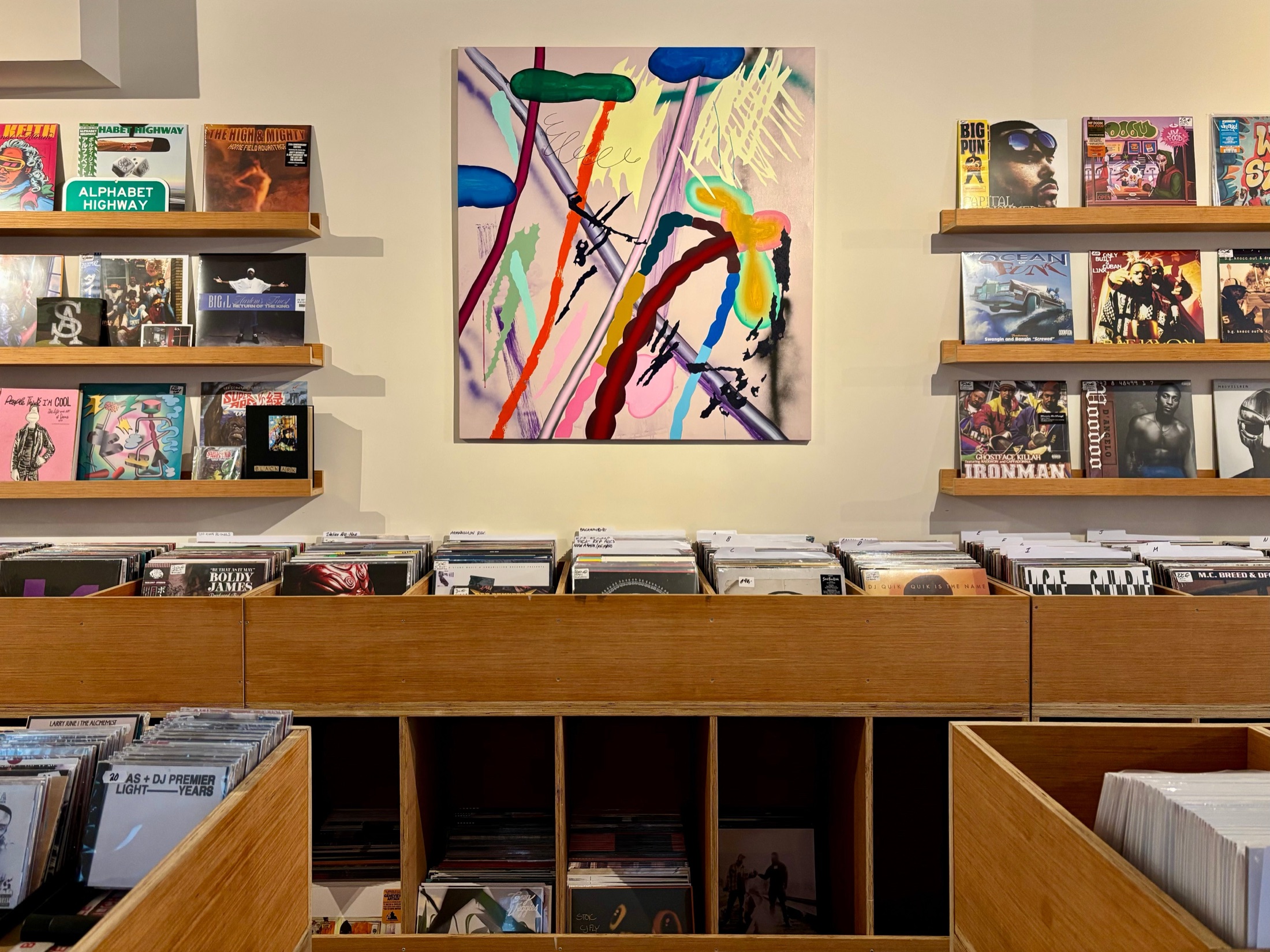 The Amsterdam store: face-out records on oak shelves either side of a painting, above plywood crates